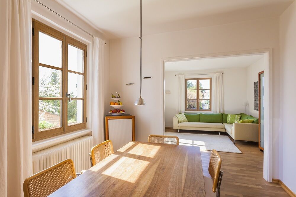 Fenêtres en bois à petits carreaux dans un intérieur lumineux avec parquet et mobilier naturel